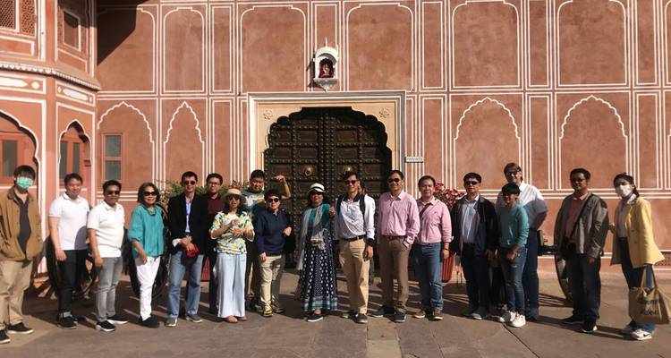 Large tour group standing together in front of an ornate doorway within a Rajasthani palace courtyard.