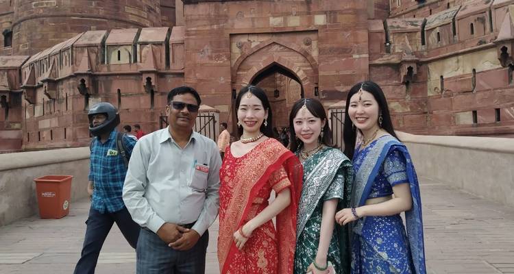 Group standing at a stone gateway of Agra Fort, with intricate red sandstone walls around.