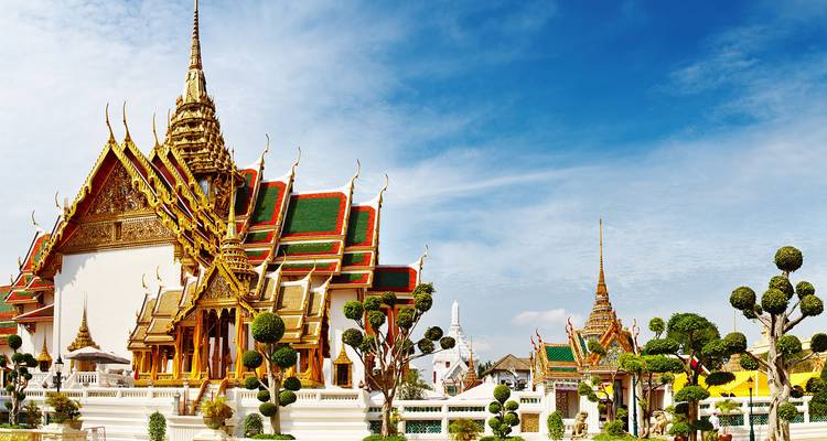 Temple thaïlandais orné aux toits dorés et aux carreaux colorés sur fond de ciel bleu éclatant