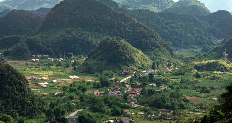 Vallée rurale parsemée de maisons et entourée de montagnes vertes ondulantes
