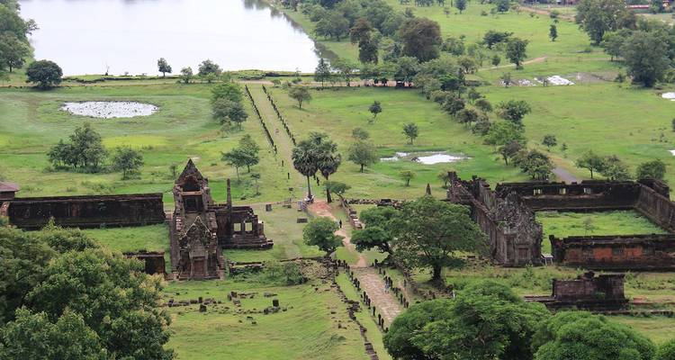 Ancient temple ruins and reservoirs scattered across a lush green plain beside a river.