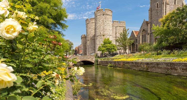 Tours médiévales de Westgate à côté d'un ruisseau cristallin et d'un jardin fleuri à Cantorbéry