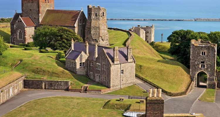 Les bâtiments en pierre et les murs du château de Douvres s'étendant le long de crêtes verdoyantes au-dessus de la mer