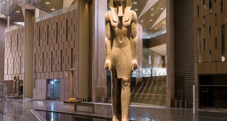 Colossal standing statue of Pharaoh Ramses II displayed inside a spacious modern museum hall.
