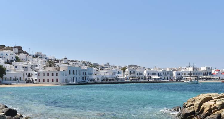 Bright white Cycladic houses line the Mykonos waterfront beside turquoise seas