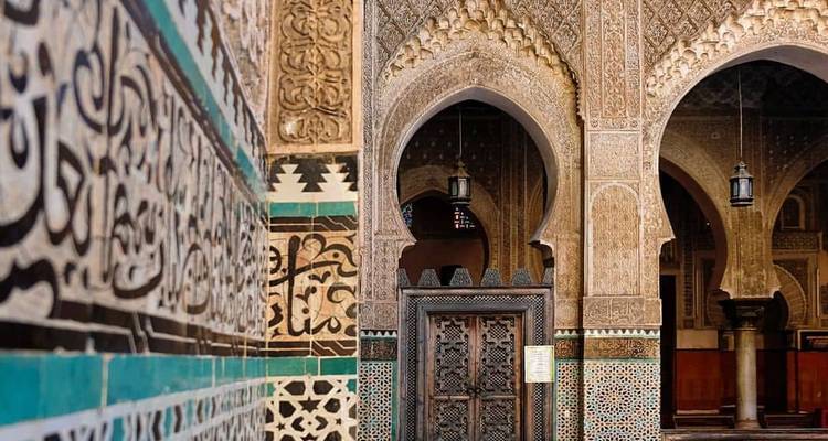 Detailed arches and mosaic tiles of an ornate Moroccan madrasa interior