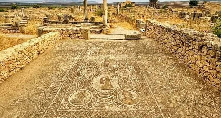 Ancient Roman mosaic floor surrounded by low stone walls at Volubilis ruins