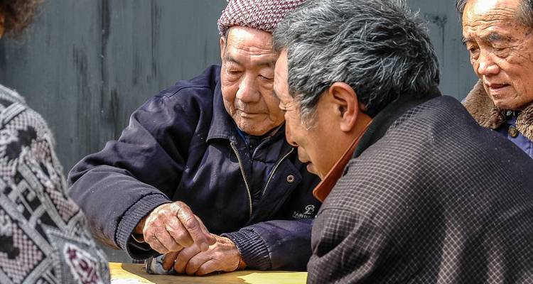 Ältere Männer, die intensiv ein Tischspiel in einer chinesischen Straßenumgebung spielen