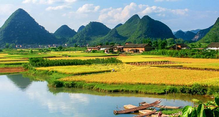 Flickwork-Reisfelder und Karstgipfel rund um ein ländliches Dorf bei Yangshuo, gespiegelt im Wasser