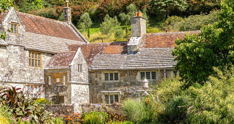 Traditionelles Landhaus aus Stein umgeben von üppigen englischen Gärten und Bäumen