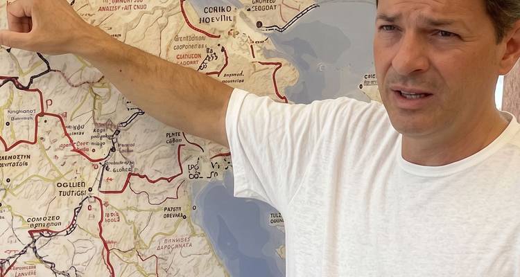 Man gestures to a detailed historical map mounted on the wall.