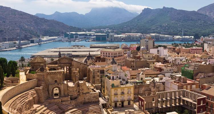 Panoramic view over Cartagena's Roman theatre and port framed by rugged mountains.