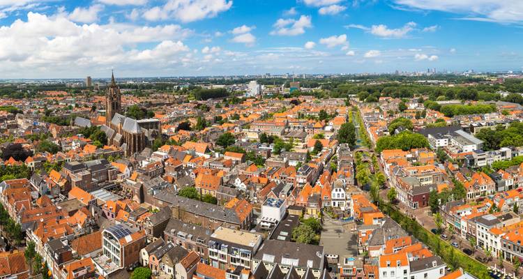 Aerial panorama of Delft with orange-tiled roofs, canals and historic church spire.