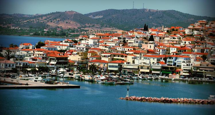 Harbor of Poros with clustered red-roof houses and hills behind calm blue water.
