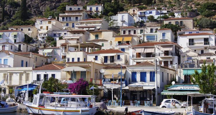 Whitewashed houses with colorful shutters stacked on a hillside above the Aegean Sea on Hydra.