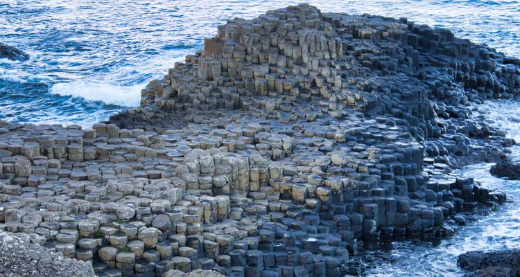 Les colonnes de basalte imbriquées de la Chaussée des Géants s'étendant dans l'Atlantique Nord bleu