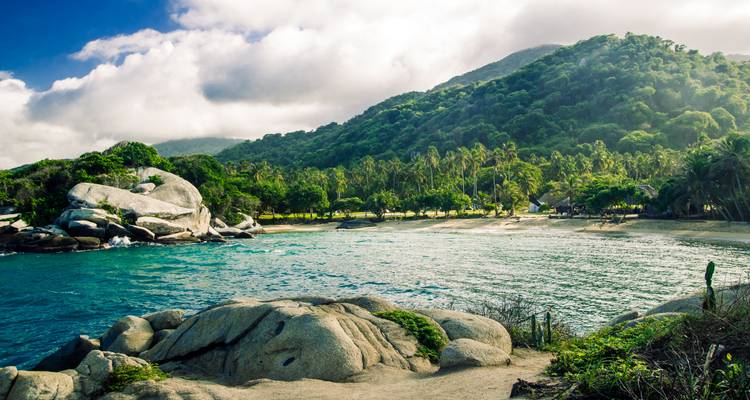 Baie turquoise bordée par des rochers de granit, une forêt de palmiers et des montagnes luxuriantes dans le parc national de Tayrona.