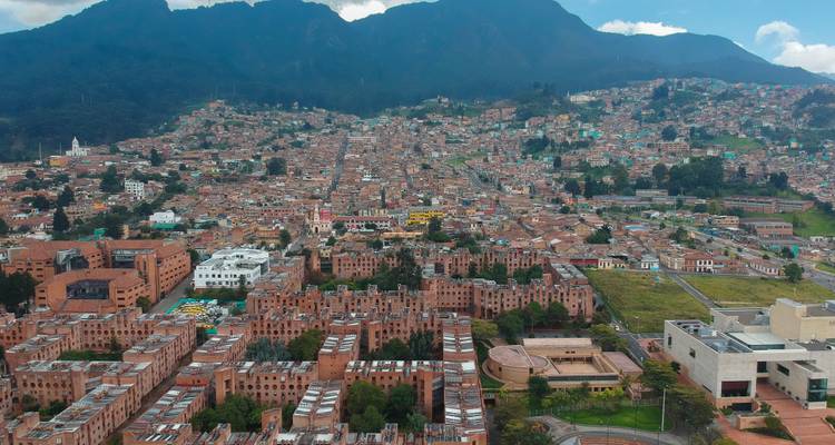 Dichte Wohnblöcke, die sich über einen Bogotá-Hang ausbreiten, mit grünen Gipfeln im Hintergrund.