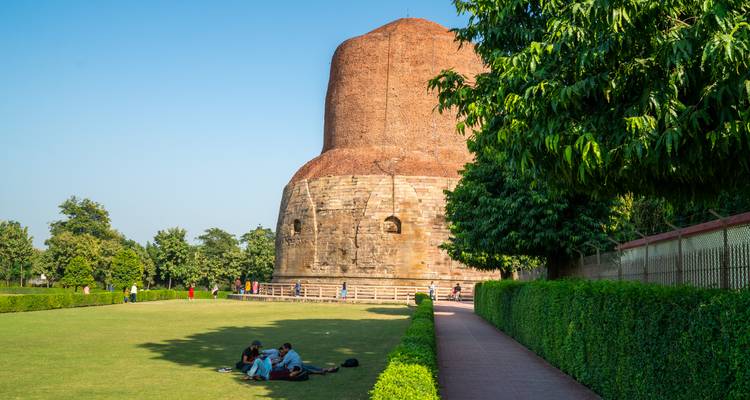 Visitors relax on the lawn near the brick Dhamek Stupa at Sarnath on a sunny day.