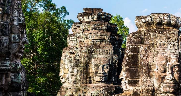 Los rostros de piedra tallada del Templo Bayon emergen de torres gastadas rodeadas de densa vegetación de la jungla.