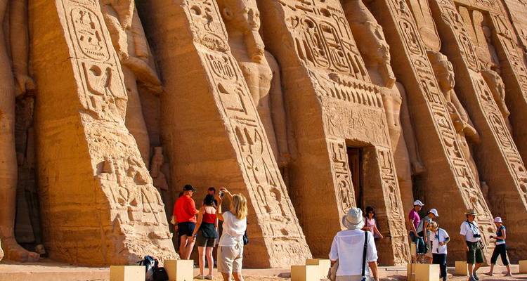 Los visitantes exploran las colosales estatuas y la fachada cubierta de jeroglíficos del templo de Abu Simbel.
