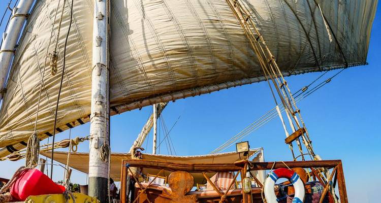 Primer plano de la enorme vela de lona de un velero tradicional ondeando contra un cielo despejado.