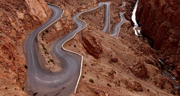 Serpentine asphalt road snaking through rugged reddish canyon walls