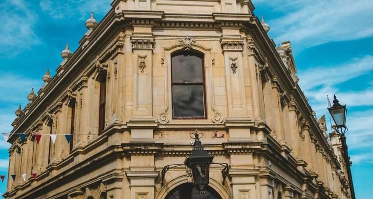 Ein verziertes Kalkstein-Viktorianer-Gebäude hebt sich gegen einen strahlend blauen Himmel in Oamaru ab.