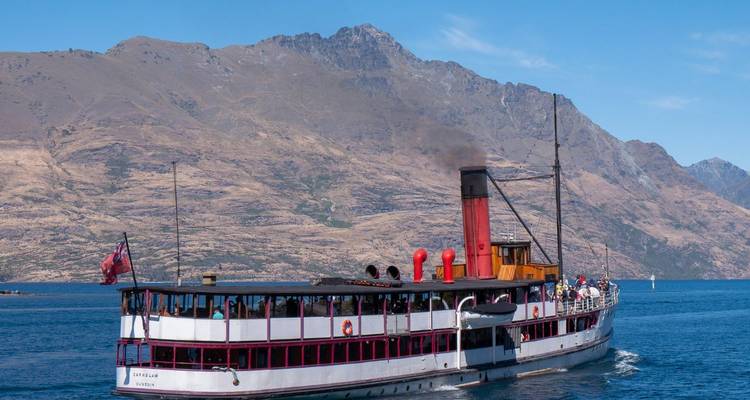 Das historische TSS Earnslaw Dampfschiff fährt auf einem tiefblauen See mit rauen Bergen im Hintergrund.