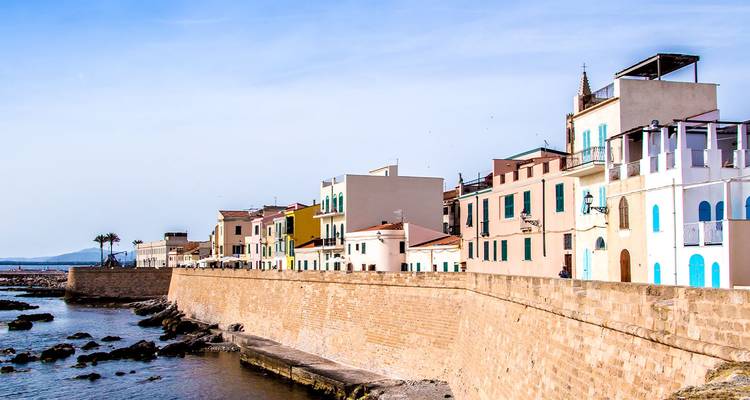 Les remparts en bord de mer et les bâtiments aux couleurs pastel de la vieille ville d'Alghero s'étendant le long du rivage