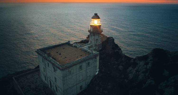 Phare solitaire brillant au crépuscule au sommet de falaises côtières escarpées