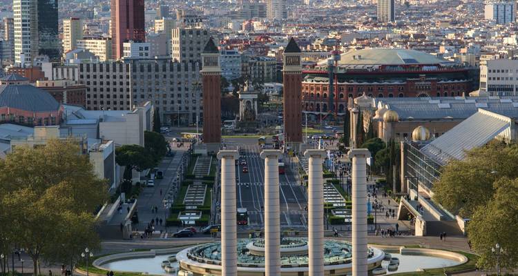 Elevated view over Barcelona’s Montjuïc fountains, columns, and city skyline at dusk
