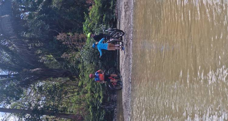 Los ciclistas se detuvieron junto a la orilla fangosa del río discutiendo la ruta mientras sus bicicletas descansaban sobre las piedras.