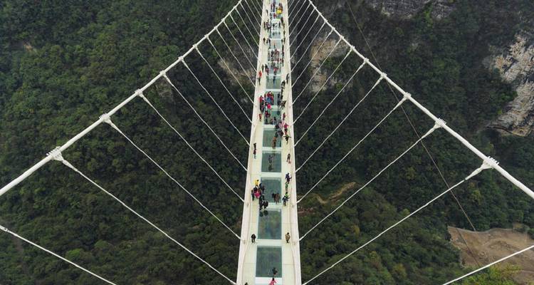 Aerial view down the glass-bottom Zhangjiajie Grand Canyon bridge crowded with visitors.