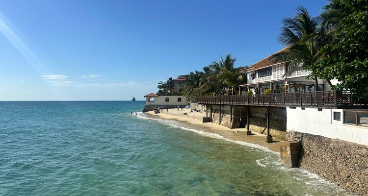 Paseo junto al mar en Stone Town con edificios históricos bordeando aguas azul cristalino