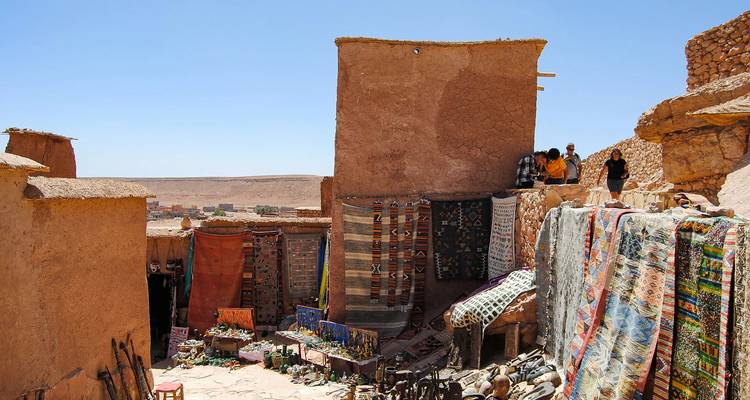 Les étals du marché berbère traditionnel avec des tapis colorés et de la poterie dans le village aux briques cuites par le soleil
