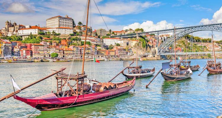 Colorful riverside houses of Porto with rabelo boats and the steel arch bridge backdrop