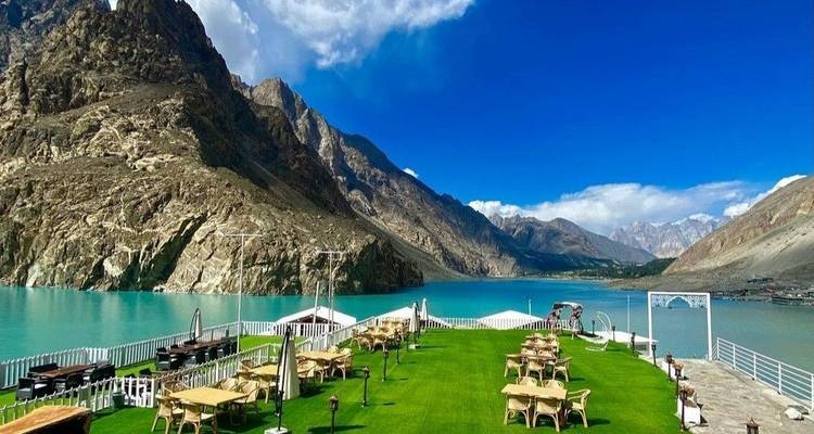 Terraza en la azotea bien cuidada con vistas a un lago alpino de color turquesa y picos rocosos espectaculares bajo un sol radiante.