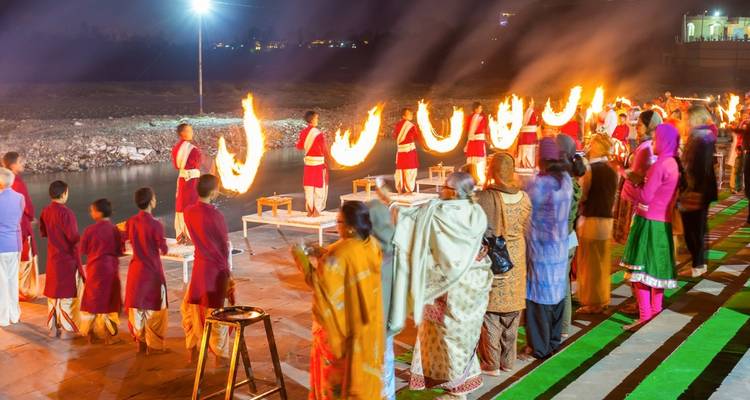 Evening Ganga Aarti ceremony with priests holding blazing torches while crowds watch along the riverbank.