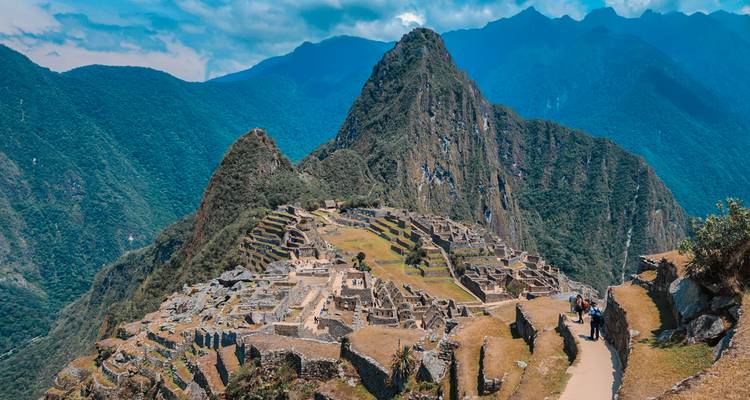 Klassiek ansichtkaartplaatje van Machu Picchu met uitzicht op de trapsgewijze ruïnes en de piek van Huayna Picchu.