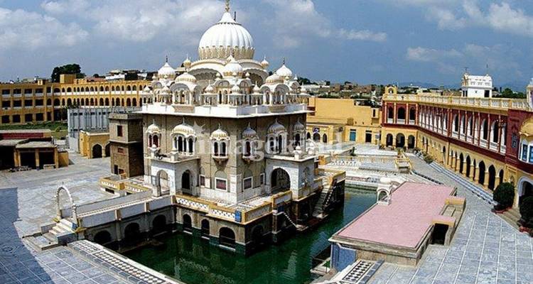 Vue élevée d'un sanctuaire sikh historique blanc et or entouré de canaux d'eau et d'une cour pavée.