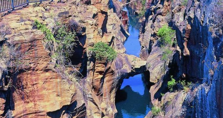 Garganta estrecha de arenisca con paredes lisas esculpidas y piscinas de agua turquesa abajo.