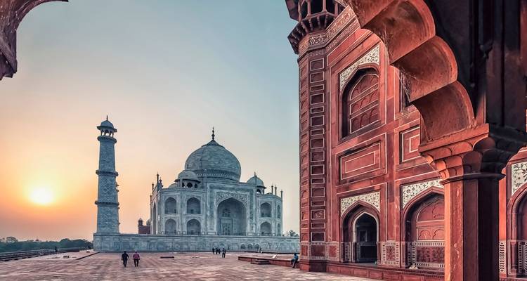 Sunrise view of Taj Mahal framed by red sandstone arch in Agra