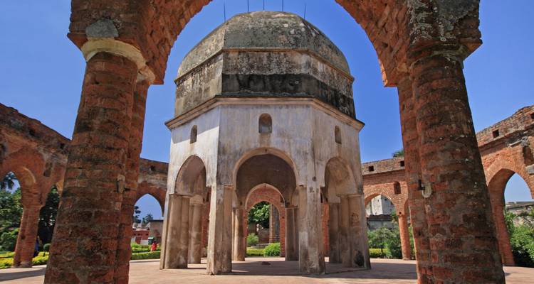 Historic octagonal dome pavilion surrounded by red brick arches under blue sky
