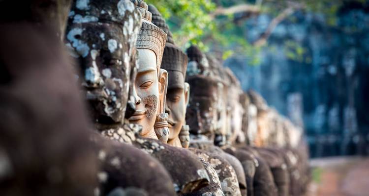 Fila de antiguas caras de guardianes de piedra alineadas en el puente de Angkor Thom.