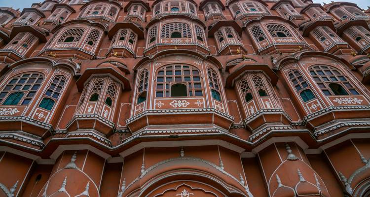 Looking up at the intricate pink lattice windows of Jaipur’s Hawa Mahal palace façade.