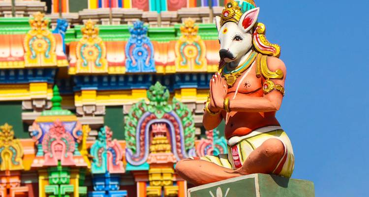Colorful Hindu temple façade with kneeling boar-headed deity statue in prayer