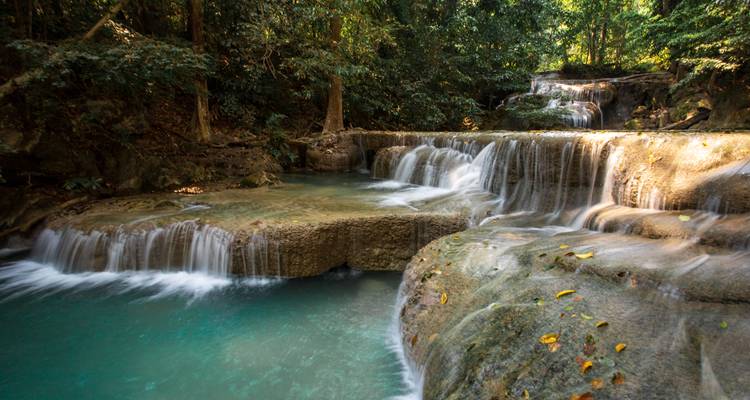 Tiered turquoise waterfall cascades through lush jungle pools.