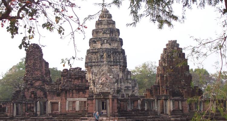 Ancient Khmer-style stone temple ruins with tiered central tower surrounded by broken walls.