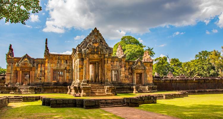 Well-preserved sandstone temple complex lit by warm sun with dramatic sky overhead.